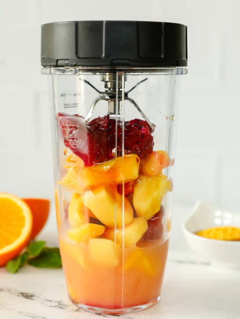 Ingredientes para un batido tropical dentro de una licuadora.