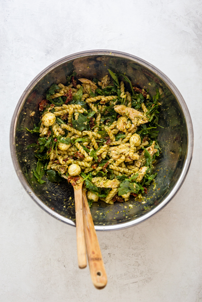 Ensalada mixta de pasta con pesto de pollo en un bol grande de acero inoxidable