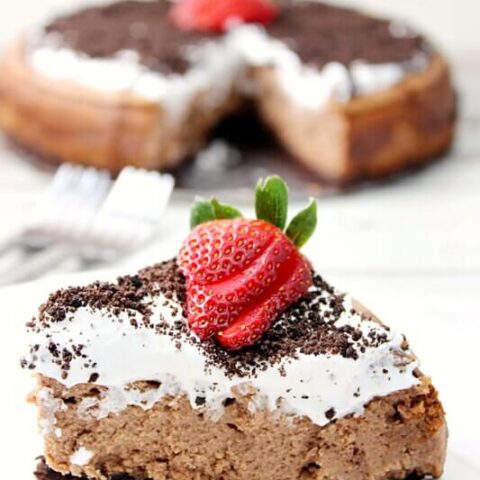 Pastel de queso con crema de chocolate irlandés Oreo con primer plano de crema batida irlandesa en un plato blanco.