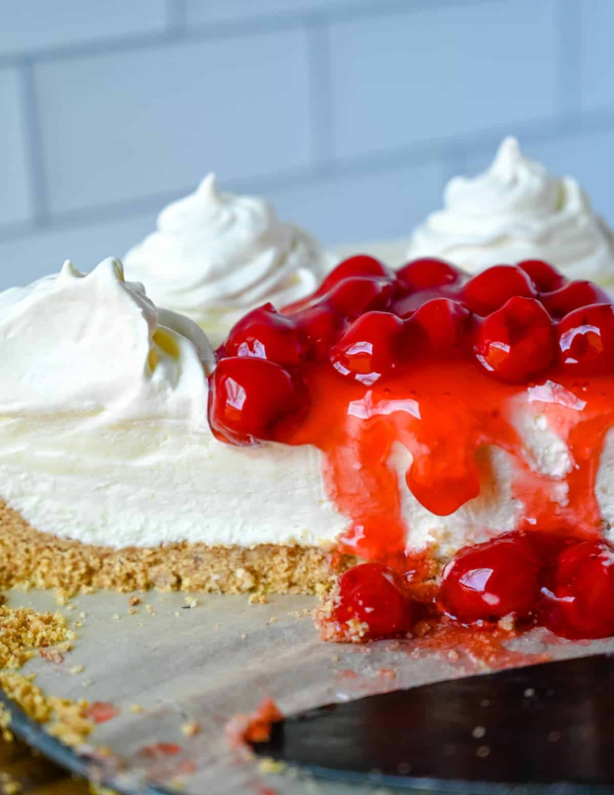 Tarta de queso sin horno cortada por la mitad con cerezas encima.