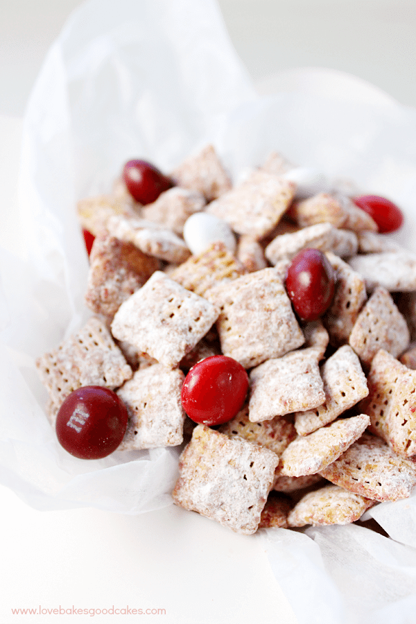 ¡Estos Muddy Buddies de Red Velvet son rápidos, fáciles y deliciosos! ¡A tu familia le encantará el toque de temporada en una delicia clásica! Amigos de barro de terciopelo rojo de cerca.