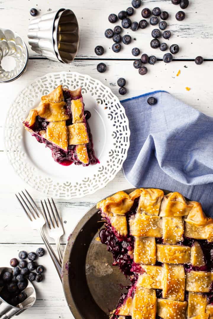 Imagen superior de un pastel de arándanos con una rebanada cortada y emplatada, con el relleno grueso para pastel de arándanos saliendo.