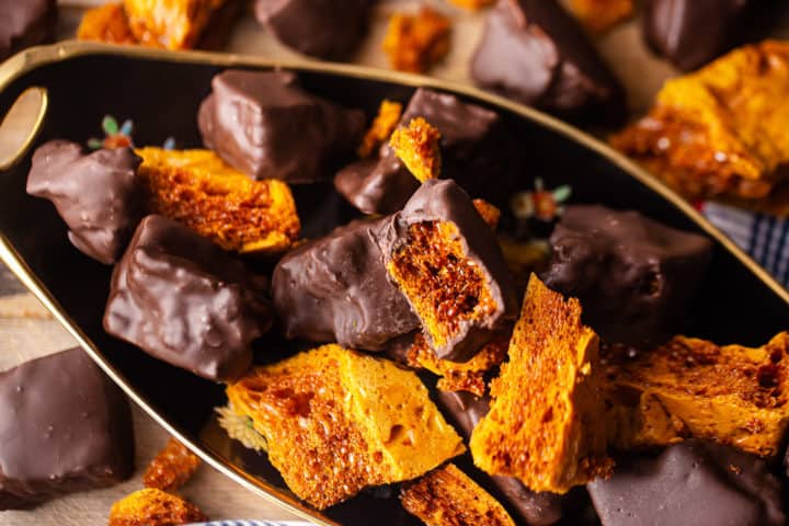 Imagen cenital de la receta de bizcocho, preparada y cubierta de chocolate, presentada sobre un fondo de madera.