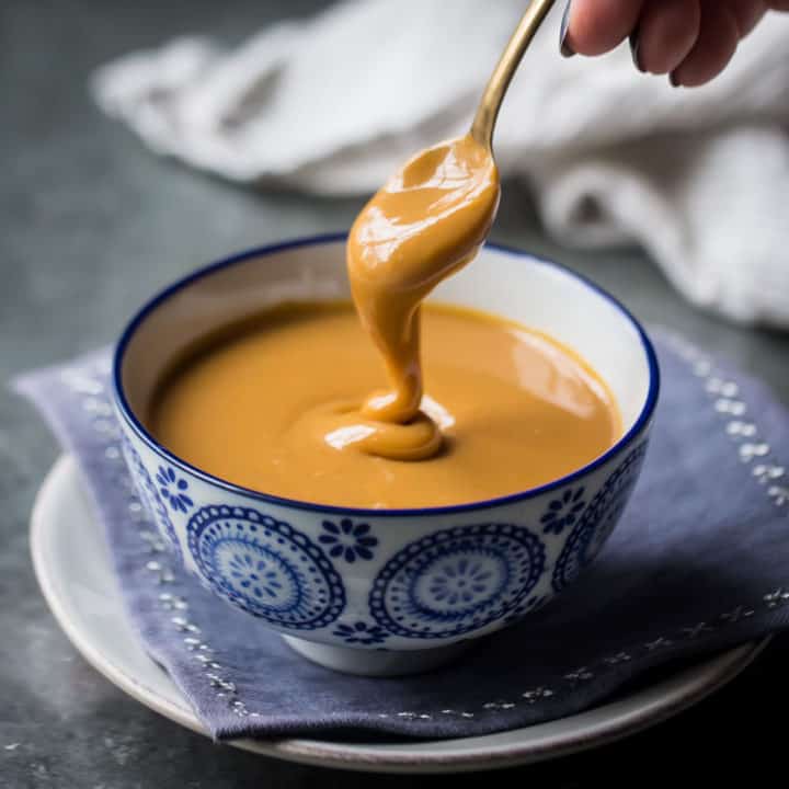 Cuchara de dulce de leche casera de un tazón azul estampado.