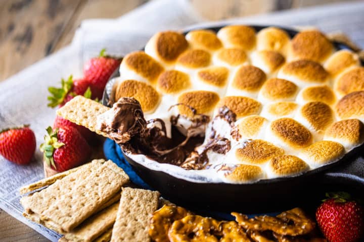 Salsa s'mores hecha al horno con una sartén, rodeada de varias conchas.