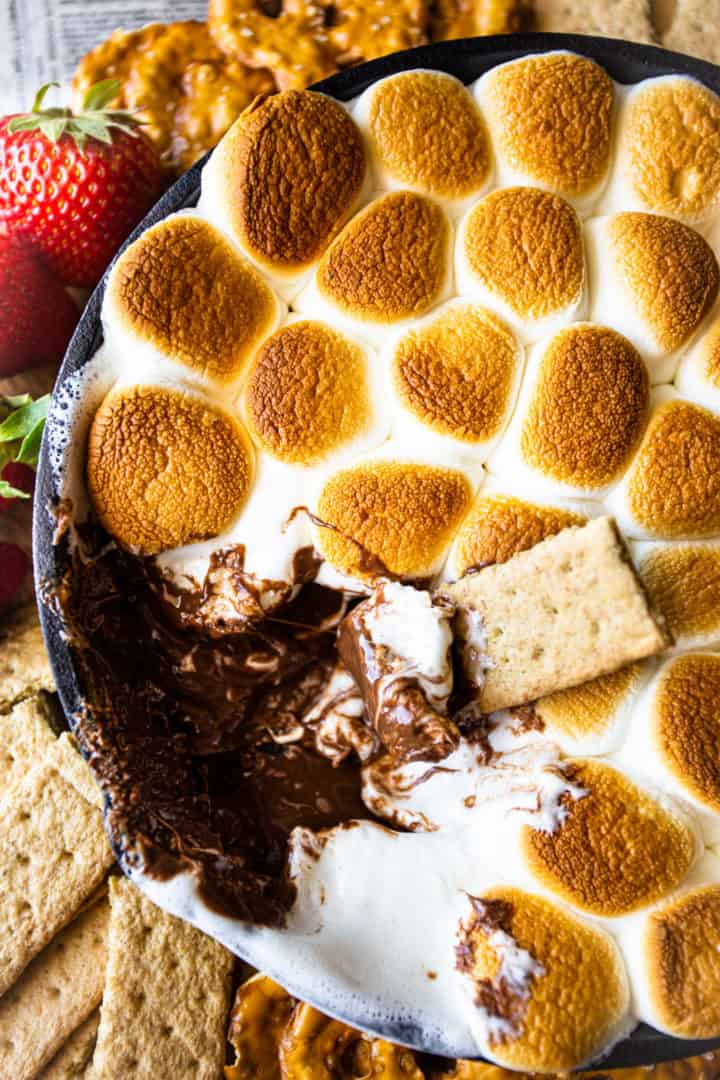 Primer plano de salsa de s'mores con chocolate derretido, malvaviscos tostados y galletas graham.