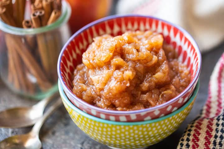 Compota de manzana casera fácil con palitos de canela en el fondo.