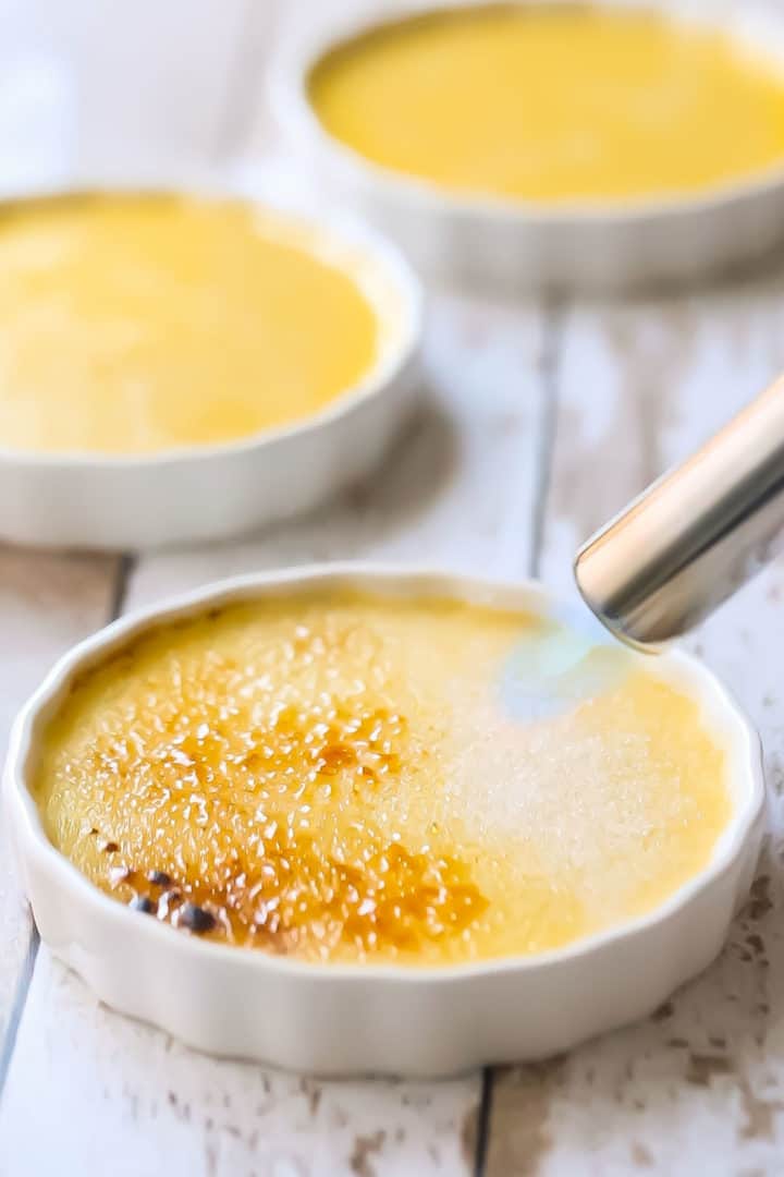Azúcar glasé brulee sobre la crème brulee con un soplete.