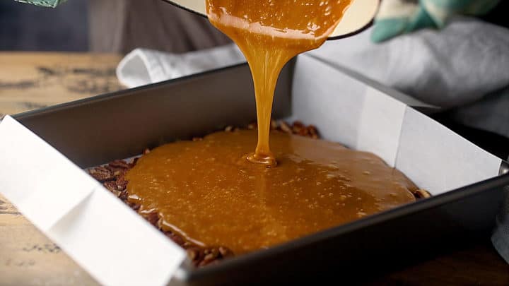 Vierta la mezcla de caramelo caliente sobre las nueces tostadas.