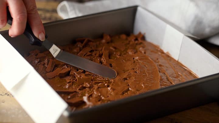 Extienda el chocolate derretido sobre el caramelo casero.