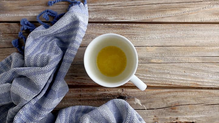 Mantequilla derretida en una taza de café de cerámica blanca.