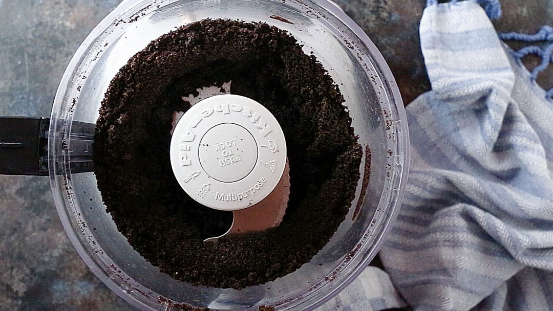 Migas de Oreo finamente picadas en el tazón de un procesador de alimentos.