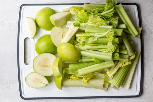 Apio y manzanas lavados y picados en una tabla de cortar
