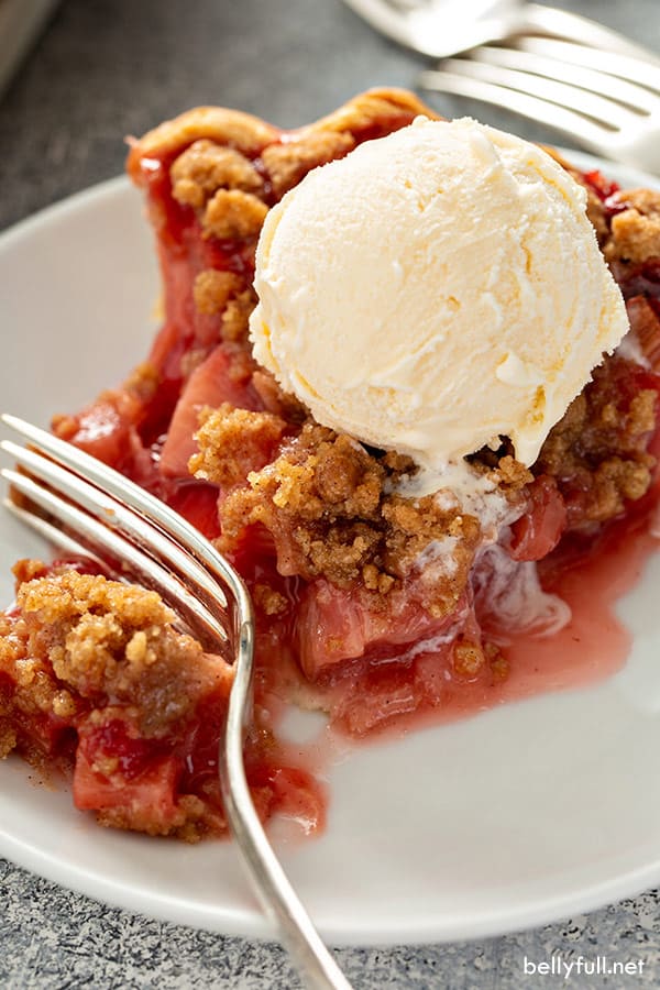 rebanada de pastel de ruibarbo de fresa con helado de vainilla en plato blanco con tenedor
