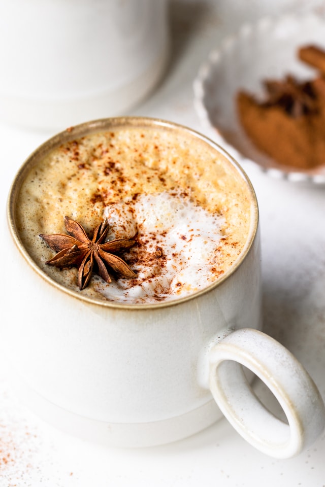 Foto de una taza en ángulo que muestra la parte superior espumosa de un café con leche casero con especias de calabaza