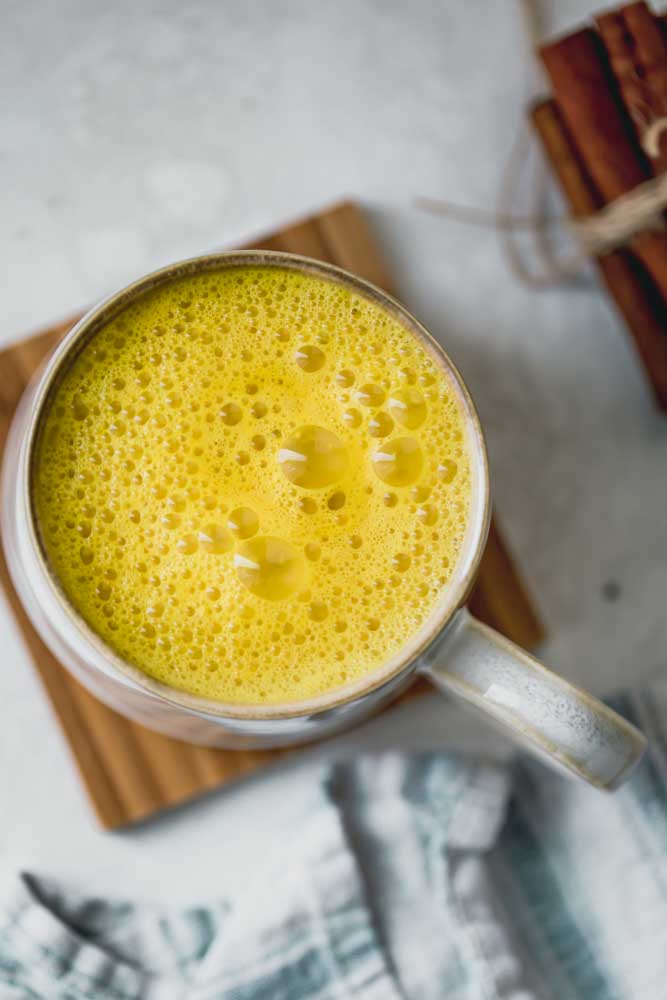 Taza grande de leche de azafrán dorado en un posavasos de madera