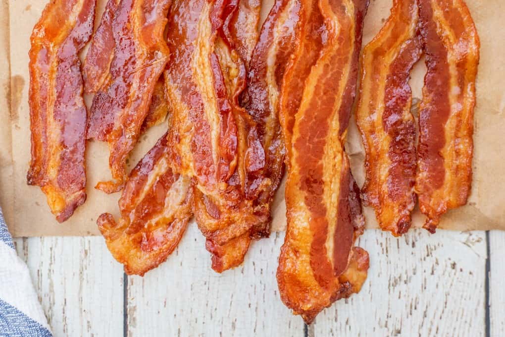 Primer plano de tocino ahumado cocido crujiente en una bolsa de papel