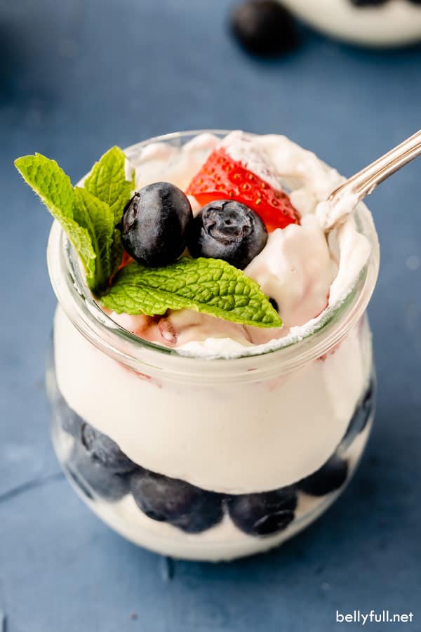 fotografía cenital de arándanos y fresas, con hoja de menta, en mousse de tarta de queso con cuchara