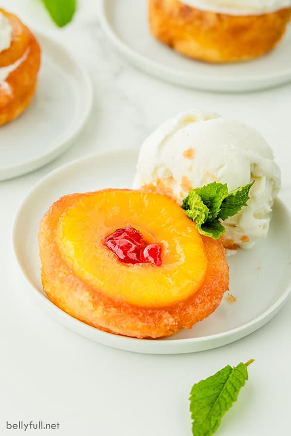 Postre de pastel al revés de piña en un plato blanco con helado de vainilla y hojas de menta fresca