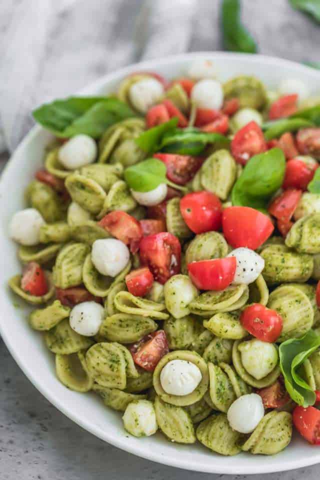 ¡El último plato de verano, esta ensalada de pasta caprese está hecha con trozos de mozzarella nacarada, suculentos tomates cherry y mezclados con un pesto brillante!