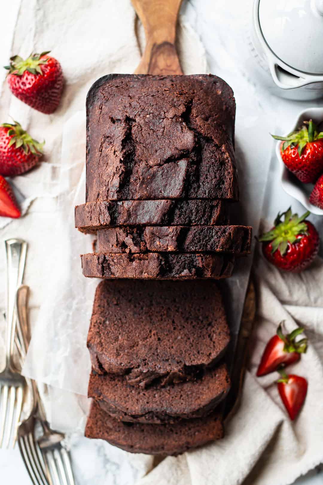 Imagen de arriba de un bizcocho de crema agria de chocolate amargo rebanado y servido en una mesa.