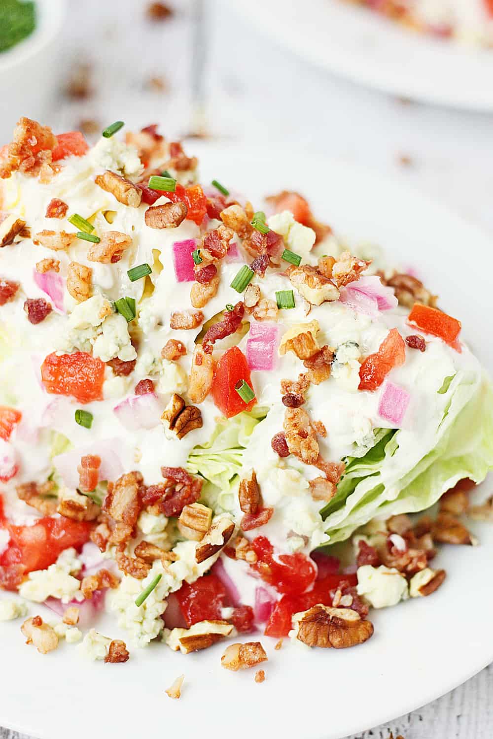 Ensalada de cuña cargada: esta ensalada de cuña cargada presenta lechuga iceberg cubierta con aderezo de queso azul, cebolla roja, tomate, tocino, migas de queso azul y nueces. ¡Es más fácil de hacer de lo que piensas! | #receta #ensalada picante