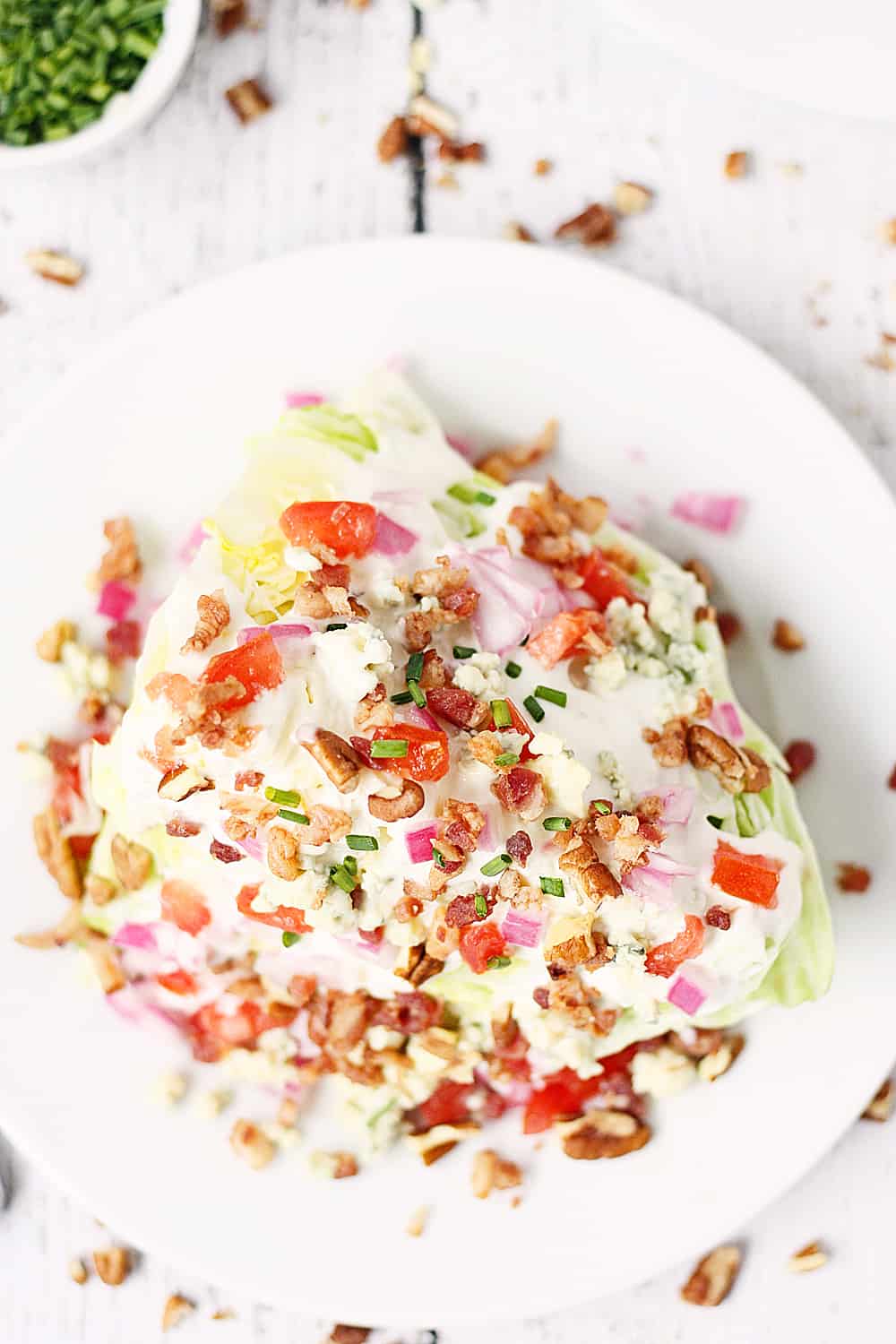 Ensalada de cuña cargada: esta ensalada de cuña cargada presenta lechuga iceberg cubierta con aderezo de queso azul, cebolla roja, tomate, tocino, migas de queso azul y nueces. ¡Es más fácil de hacer de lo que piensas! | #receta #ensalada picante