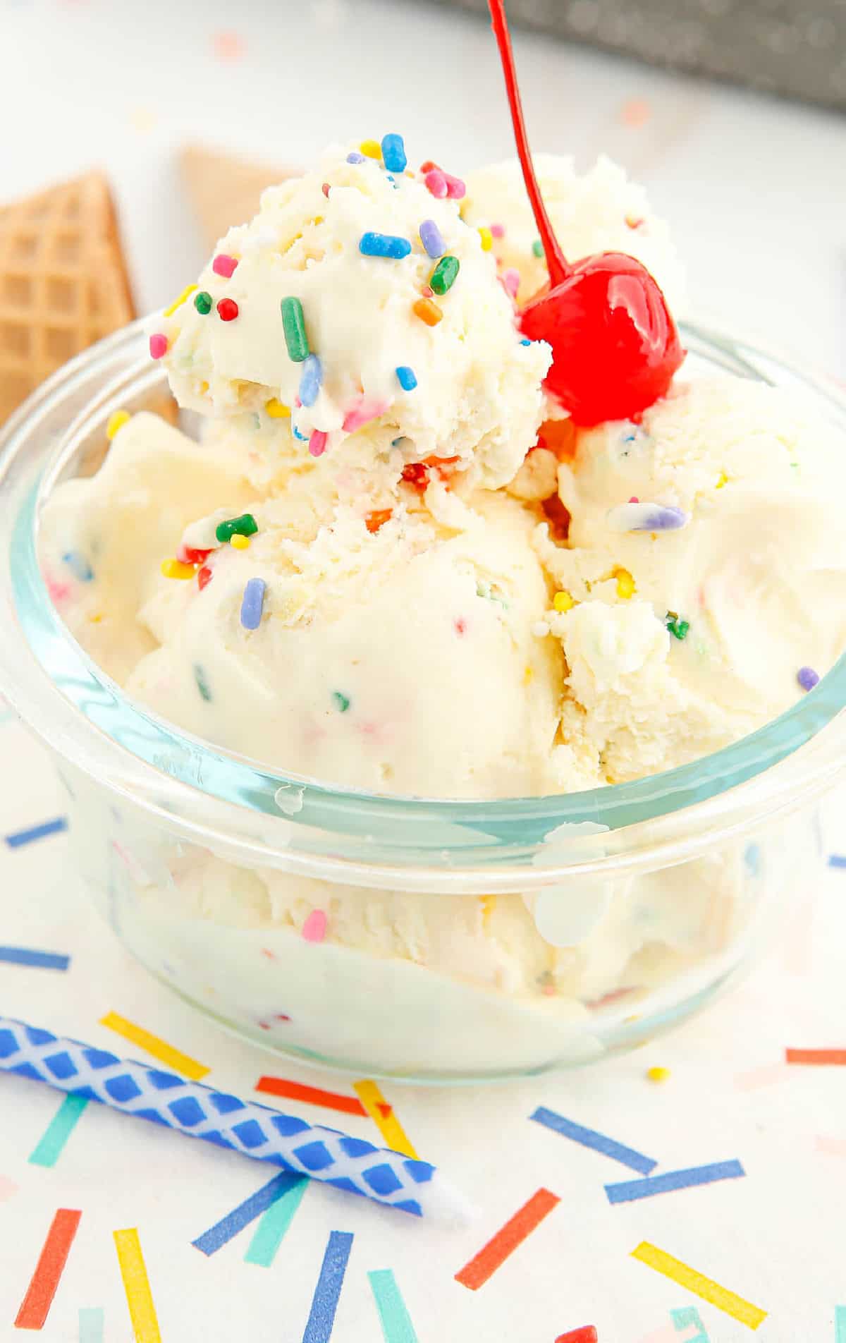 Una taza de helado de pastel de cumpleaños con una cereza encima.