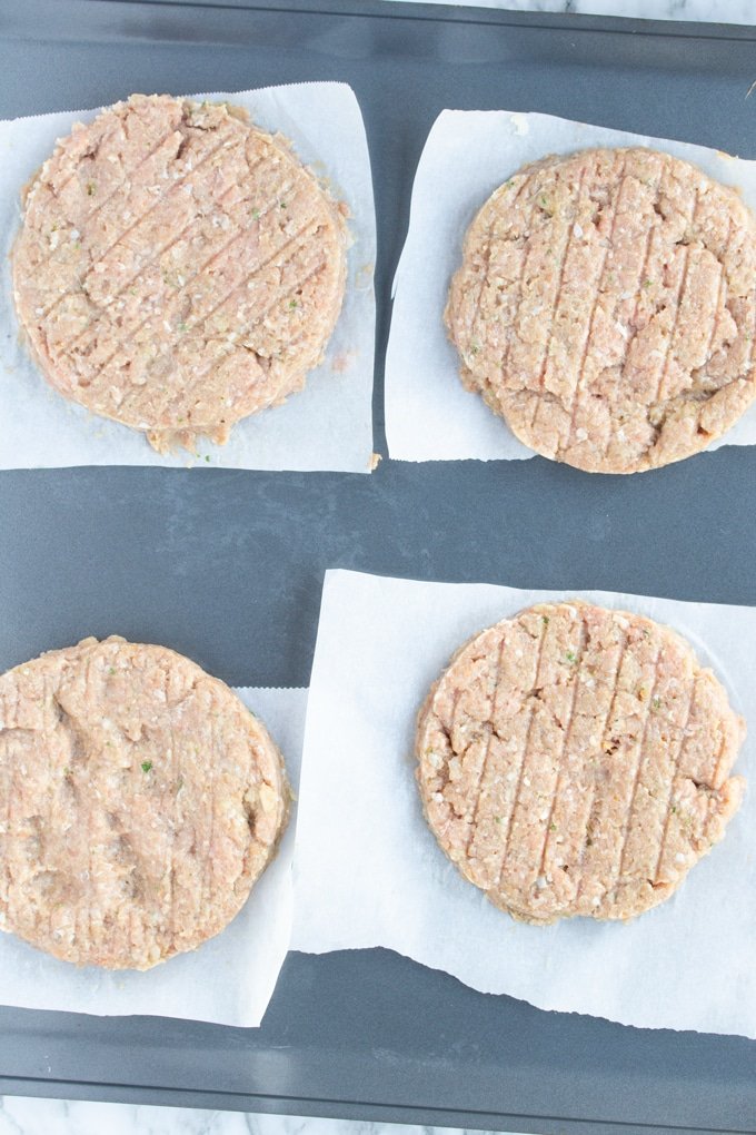 cuatro hamburguesas de pavo crudas en papel pergamino