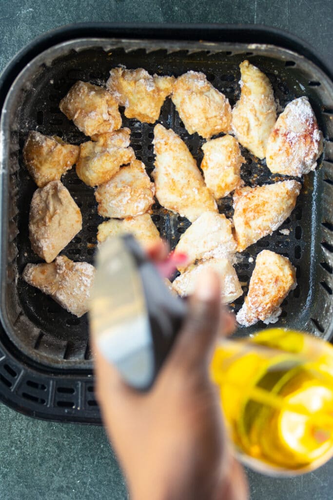 Pollo en la canasta con botella de spray encima de la canasta