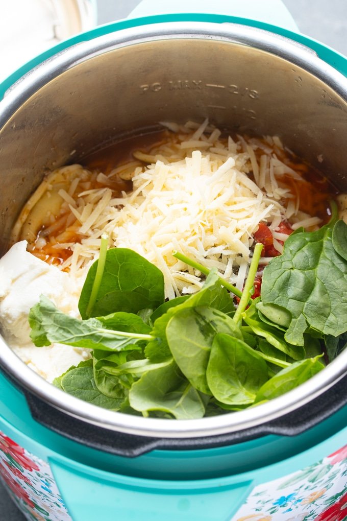 todos los ingredientes dentro de la olla instantánea, queso y espinacas encima